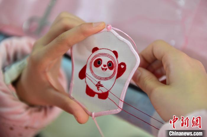 圖為一名小學生正在繡制2022年北京冬奧會吉祥物“冰墩墩”形象?！∮髟屏?攝