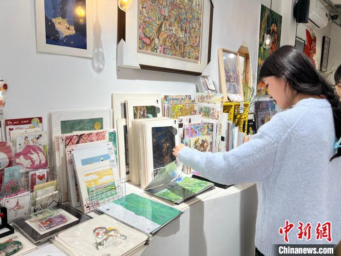 圖為藝術(shù)品商店內(nèi)，顧客挑選插畫作品?！＄婌?攝