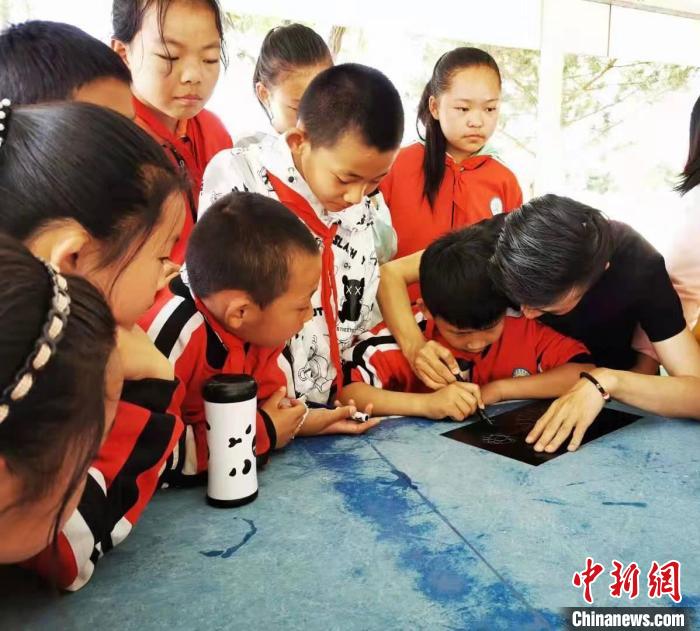 圖為朱增平(右一)教學(xué)生創(chuàng)作鍥金畫。(資料圖) 受訪者供圖