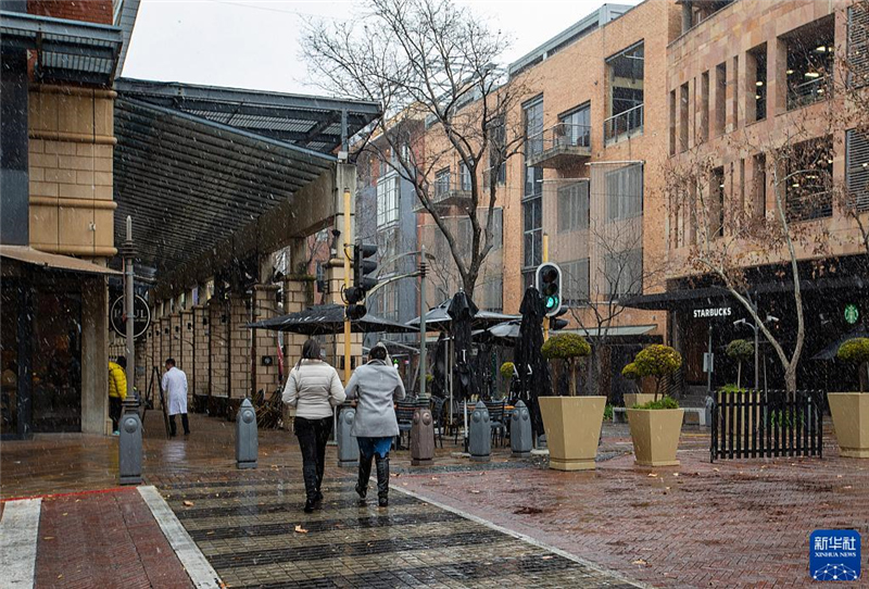 7月10日，在南非約翰內斯堡一處商業(yè)區(qū)，人們在雪中行走。新華社記者 張譽東 攝