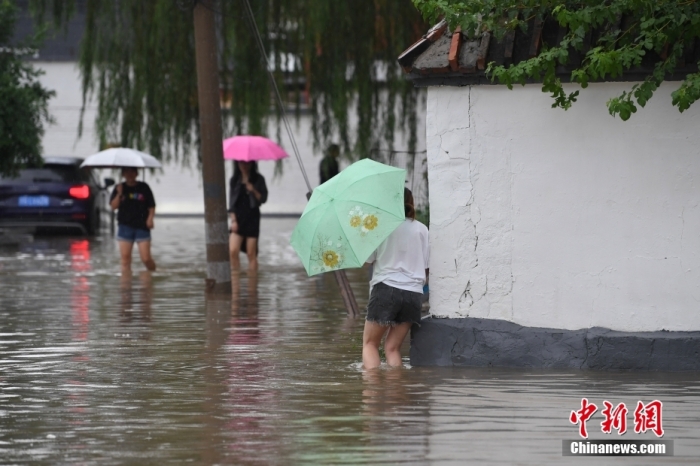 7月31日，市民行走在雨中的北京房山區(qū)瓦窯頭村。北京市氣象臺(tái)當(dāng)日10時(shí)發(fā)布分區(qū)域暴雨紅色預(yù)警信號(hào)。北京市水文總站發(fā)布洪水紅色預(yù)警，預(yù)計(jì)當(dāng)日12時(shí)至14時(shí)，房山區(qū)大石河流域?qū)⒊霈F(xiàn)紅色預(yù)警標(biāo)準(zhǔn)洪水。<a target='_blank' href='/'><p  align=