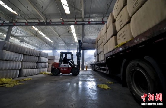新疆喀什綜合保稅區(qū)，喀什啟路國際貿(mào)易有限公司的倉庫內(nèi)，工人正在裝載從塔吉克斯坦和烏茲別克斯坦進(jìn)口的棉花。劉新攝