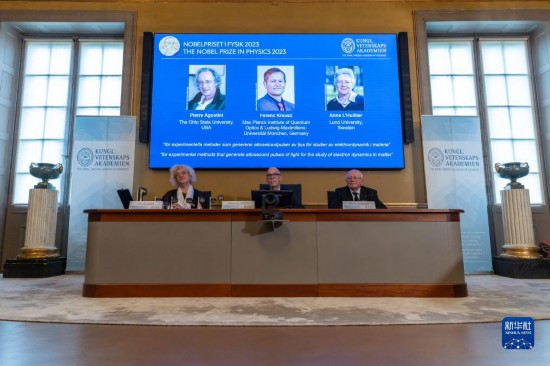 10月3日，在瑞典斯德哥爾摩舉行的2023年諾貝爾物理學(xué)獎公布現(xiàn)場，屏幕上顯示獎項(xiàng)得主皮埃爾·阿戈斯蒂尼（左）、費(fèi)倫茨·克勞斯（中）和安妮·呂利耶的照片。新華社發(fā)（魏學(xué)超攝）