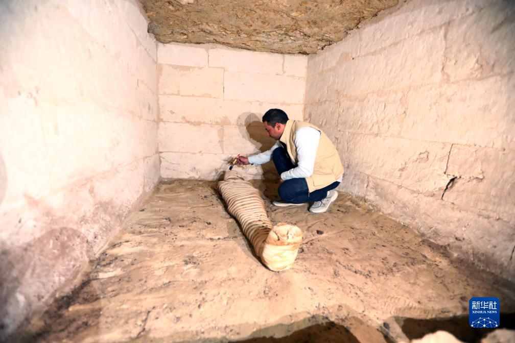 10月15日，在埃及明亞省考古現(xiàn)場，考古人員清理一座石鑿墓中的木乃伊。新華社發(fā)（艾哈邁德·戈馬攝）