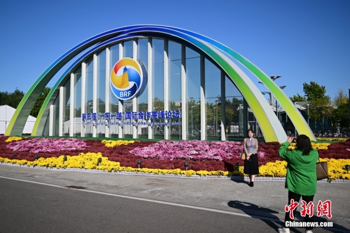 10月15日，北京，工作人員在國家會議中心外的第三屆“一帶一路”國際合作高峰論壇景觀布置前拍照留念。當(dāng)日，位于國家會議中心的第三屆“一帶一路”國際合作高峰論壇新聞中心啟動試運(yùn)行。據(jù)悉，第三屆“一帶一路”國際合作高峰論壇將于10月17日至18日在北京舉行。<a target='_blank' href='/'><p  align=