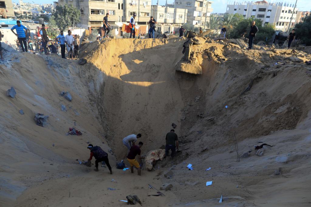 10月16日，在加沙地帶南部城市汗尤尼斯，人們在遭以色列襲擊后的建筑廢墟中救援傷者。 新華社發(fā)（亞西爾·庫迪 攝）
