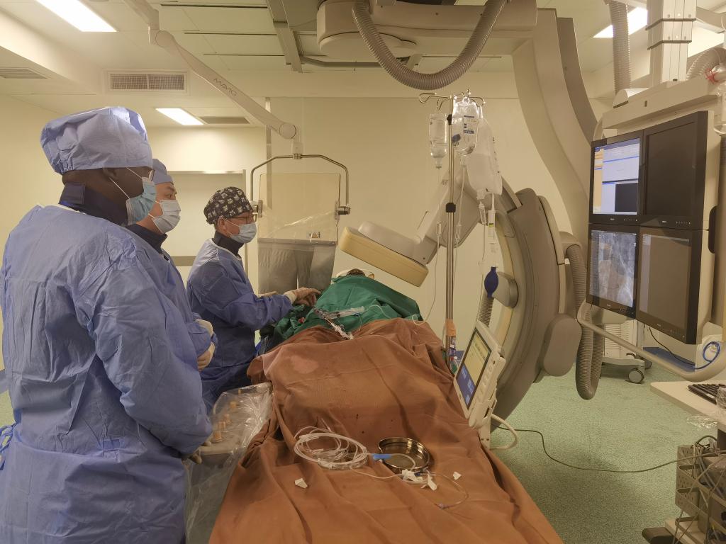 中國第29批援幾內(nèi)亞醫(yī)療隊隊員、首都醫(yī)科大學(xué)附屬北京天壇醫(yī)院心內(nèi)科副主任醫(yī)師王汝朋（右一）正在給患者做手術(shù)。（北京天壇醫(yī)院供圖）