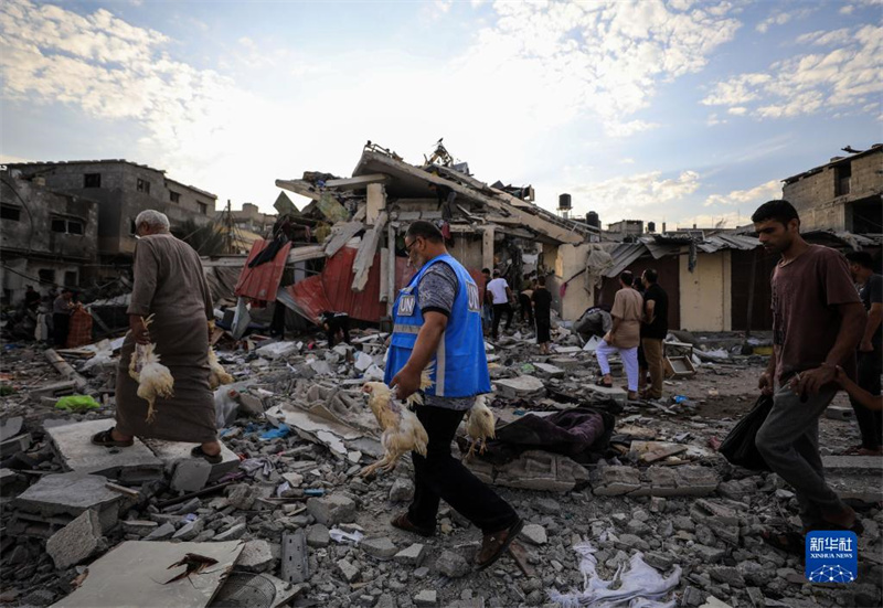 10月27日，在加沙地帶南部城市汗尤尼斯，人們經(jīng)過以軍襲擊后的房屋廢墟。