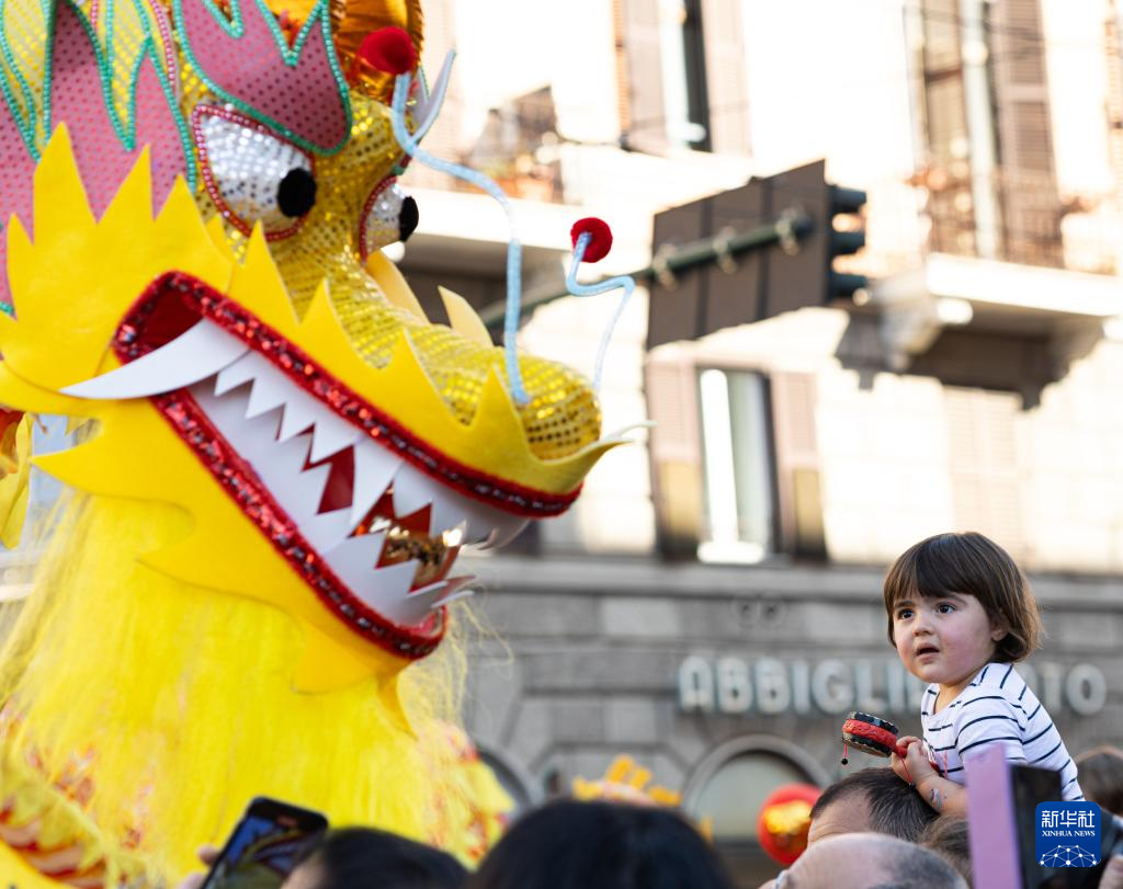 2月18日，在意大利羅馬，一名小朋友在彩妝巡游上觀看舞龍。新華社記者 李京 攝