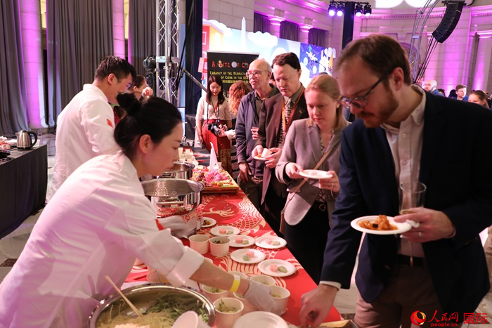 當?shù)貢r間3月7日晚，華盛頓聯(lián)合車站廣場舉行駐美使團“使館主廚挑戰(zhàn)賽”。圖為當?shù)孛癖娫谥袊古_前體驗中國美食。人民網(wǎng)記者 李志偉攝