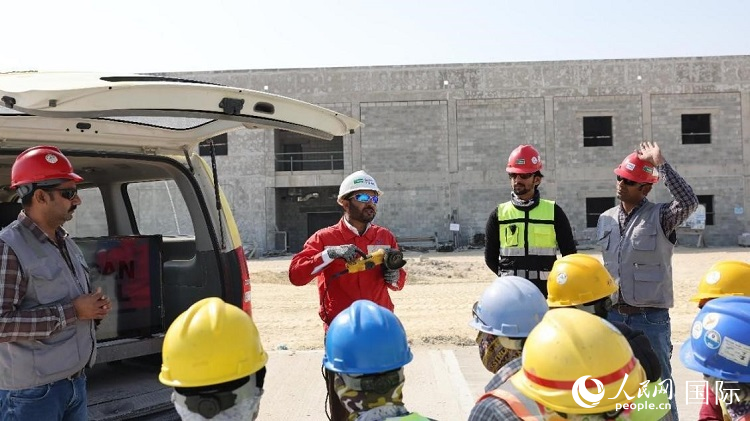 穆薩瓦爾(圖中紅衣人）現場演示工具操作規(guī)范。人民網記者 管克江攝