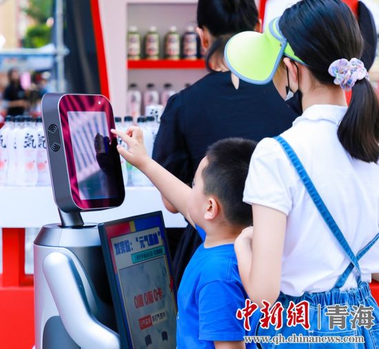 圖為一名小朋友正在和機(jī)器人“志愿者”進(jìn)行互動(dòng)。 沐聞 攝