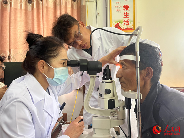 王紅英（左）和團隊成員為達熱村村民檢查眼睛。人民網記者 杜燕飛攝