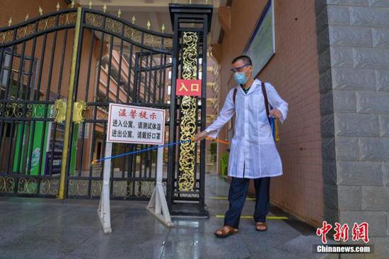 資料圖：海口經(jīng)濟(jì)學(xué)院的工作人員在學(xué)生宿舍樓入口消毒。 中新社記者 駱云飛 攝