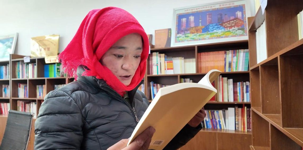 一名婦女正在認真閱讀書籍。申扎縣融媒體中心供圖