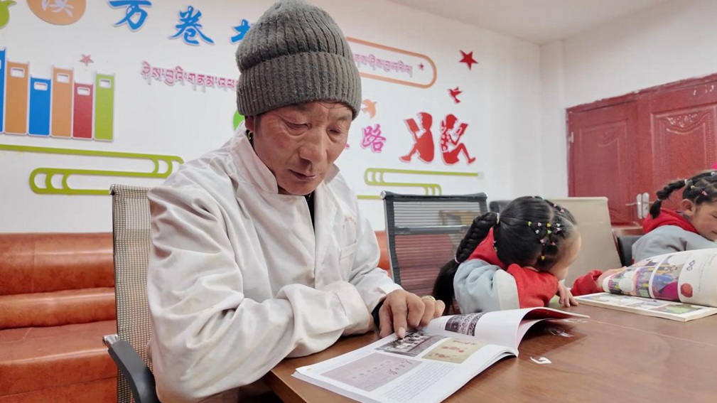 一位當?shù)卮迕窈秃⒆觽冊谀良視堇锉M情享受閱讀時光。申扎縣融媒體中心供圖