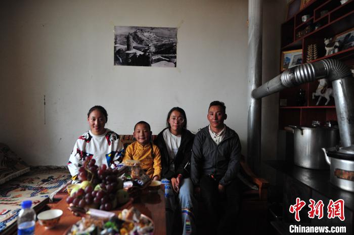 圖為8月12日，2018年7月從距那曲市色尼區(qū)城區(qū)那曲鎮(zhèn)90千米外的古露鎮(zhèn)當(dāng)桑村搬遷至城區(qū)的旦增(右一)與家人在80多平方米的新家合影(資料圖)。　張偉 攝