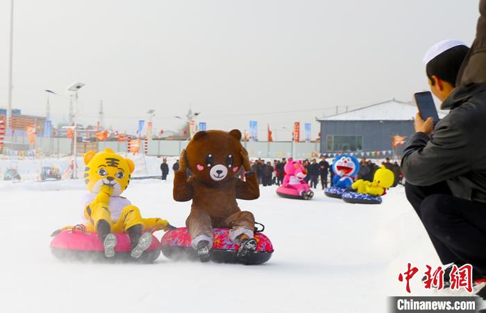 圖為臨夏市南龍鎮(zhèn)馬家莊村舉辦的鄉(xiāng)村文化旅游節(jié)上，游客穿著卡通服裝在體驗雪上飛碟項目。近年來，臨夏州形成了“春賞花、夏避暑、秋摘果、冬玩雪”的全季節(jié)旅游產(chǎn)品體系。(資料圖) 高展 攝