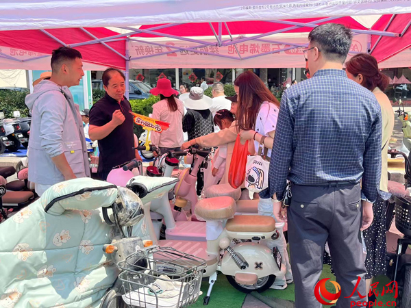 某電動(dòng)自行車品牌工作人員向消費(fèi)者介紹以舊換新相關(guān)情況。人民網(wǎng)記者 杜燕飛攝