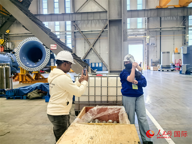 外媒記者掂量廠房內(nèi)的巨型螺栓。人民網(wǎng) 楊春燕攝