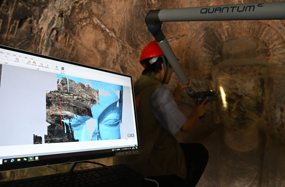 2025年4月9日，武漢大學文化遺產智能計算實驗室團隊成員在魏字洞使用關節(jié)臂掃描儀對佛像進行數(shù)字化掃描。圖片來源新華社