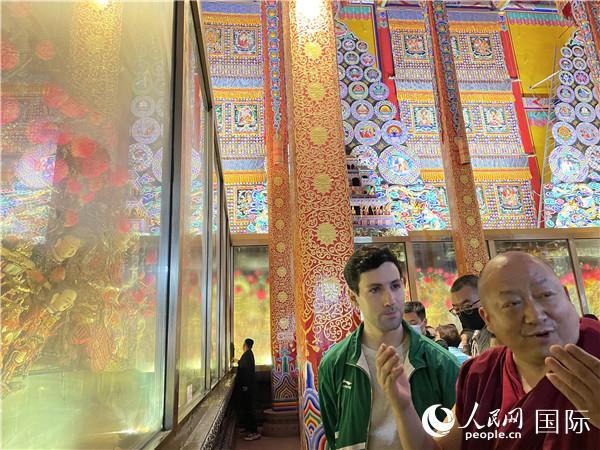 7月25日，省級(jí)非物質(zhì)文化遺產(chǎn)項(xiàng)目塔爾寺酥油花的代表性傳承人朋措堅(jiān)參（右）在塔爾寺酥油花館講解酥油花的制作過(guò)程。人民網(wǎng) 謝瑩攝