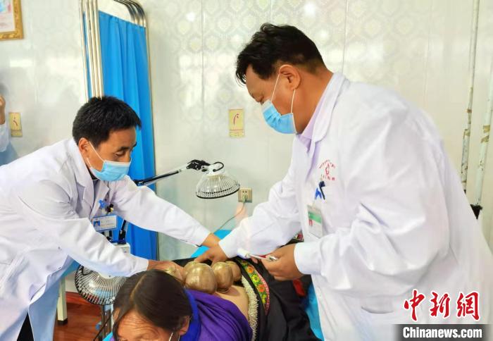 圖為看照加手把手帶徒弟加老(左一)進(jìn)行拔罐療法。　張婧 攝