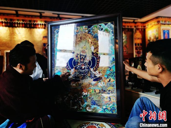 圖為久美尖措(左)與徒弟們展示唐卡作品?！?zhí)砀?攝