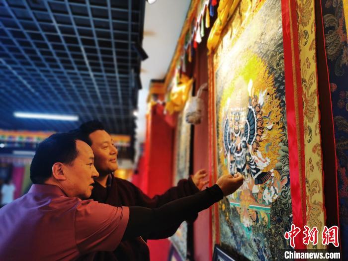 圖為久美尖措展示唐卡作品?！?zhí)砀?攝