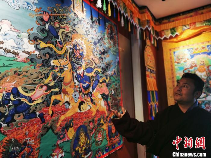 圖為久美尖措展示唐卡作品?！?zhí)砀?攝