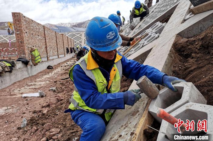 圖為光伏發(fā)電項目施工區(qū)工人在護(hù)坡鋪設(shè)空心磚?！±铍h 攝