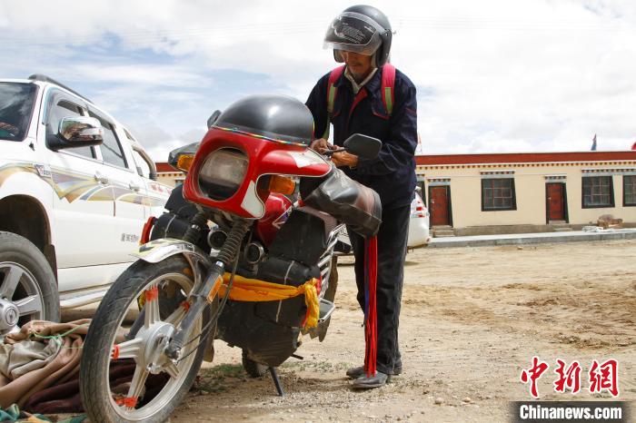 圖為白瑪準(zhǔn)備騎摩托車巡湖?！≮w朗 攝