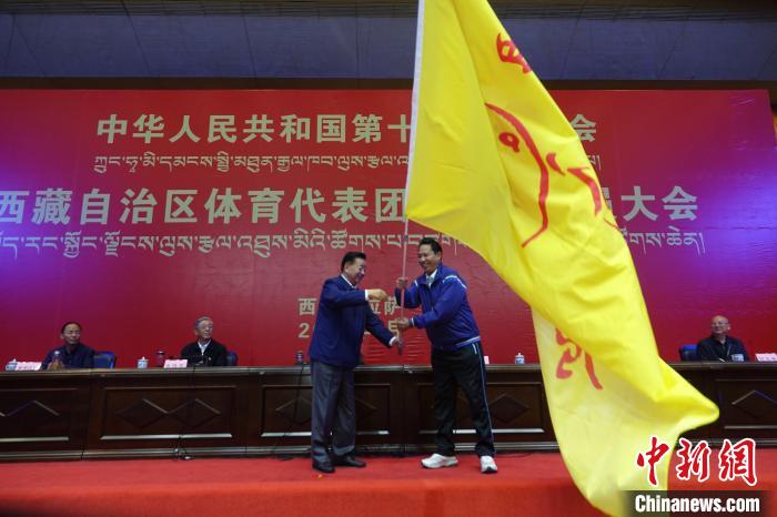 西藏自治區(qū)副主席甲熱·洛桑丹增授代表團(tuán)團(tuán)旗，西藏自治區(qū)體育局局長(zhǎng)尼瑪次仁接旗?！∪轿木?攝