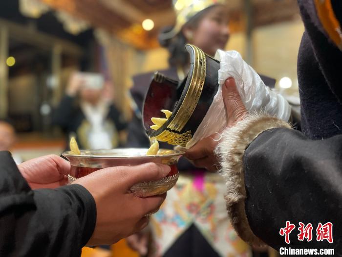 圖為主人在碗中斟滿青稞酒。　冉文娟 攝