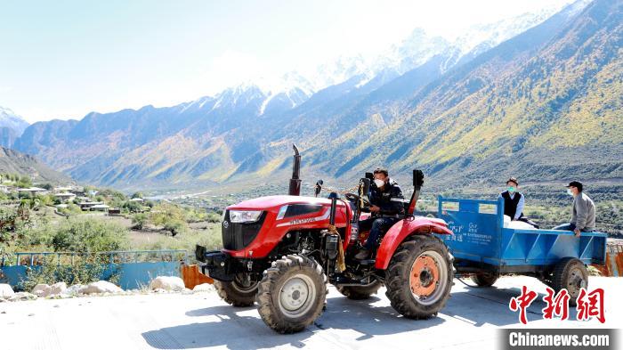 圖為工作人員將把加工完成的糌粑運(yùn)送至村民手中?！〖卫杩h融媒體中心供圖