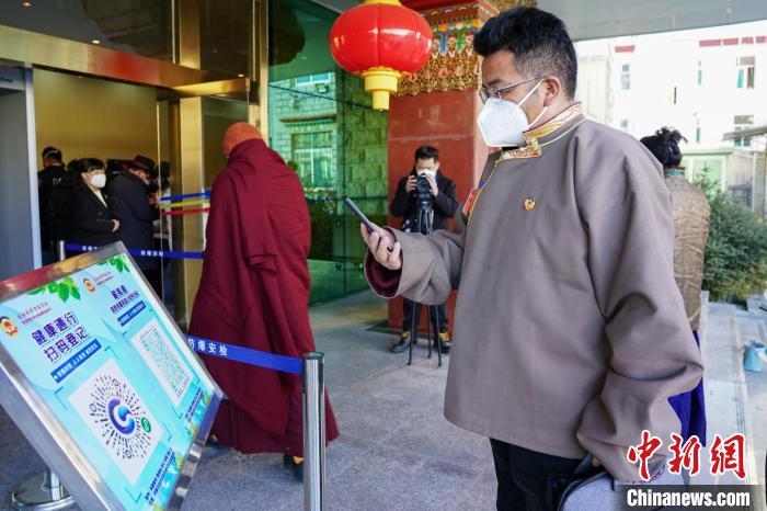 圖為政協(xié)委員掃場所碼進(jìn)入會場?！〗w波 攝