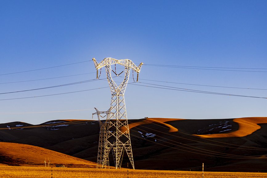 阿里地區(qū)的曠野上，電力鐵塔在夕陽(yáng)下熠熠生輝。