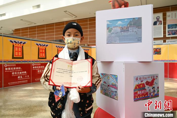 圖為一名獲獎學生與自己的繪畫作品合影?！≮w朗 攝