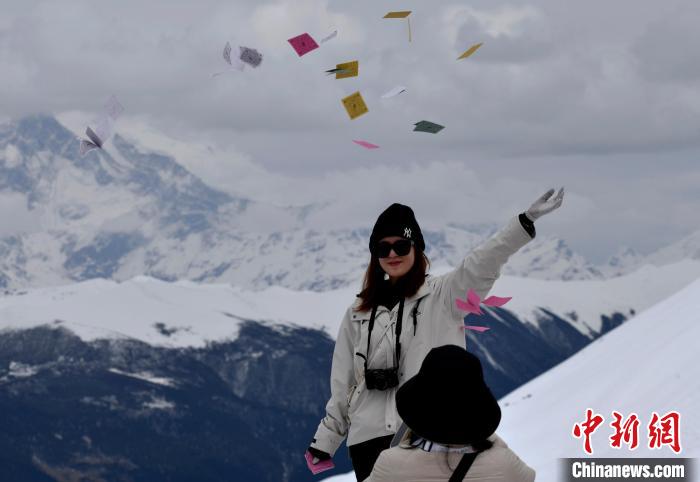圖為5月14日，游客在西藏林芝色季拉山觀景臺拋灑“隆達(dá)”(風(fēng)馬旗，藏族民眾的一種祈福方式)?！±盍?攝