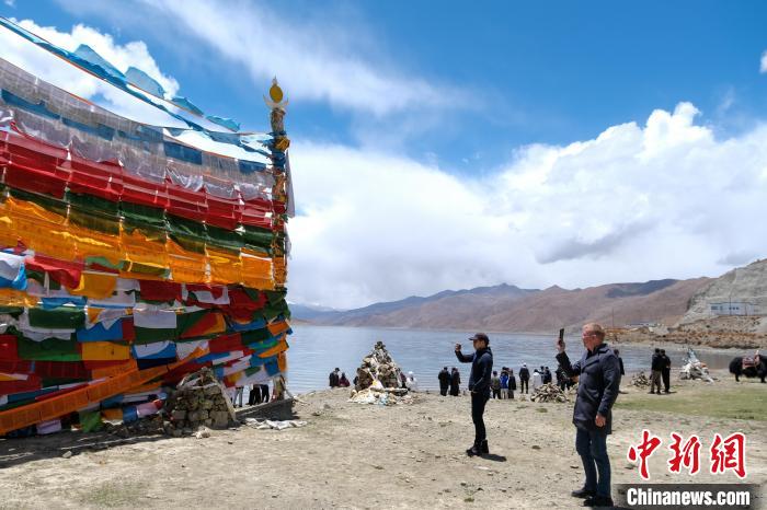 進(jìn)藏參訪嘉賓在羊湖畔拍攝經(jīng)幡?！〗w波 攝