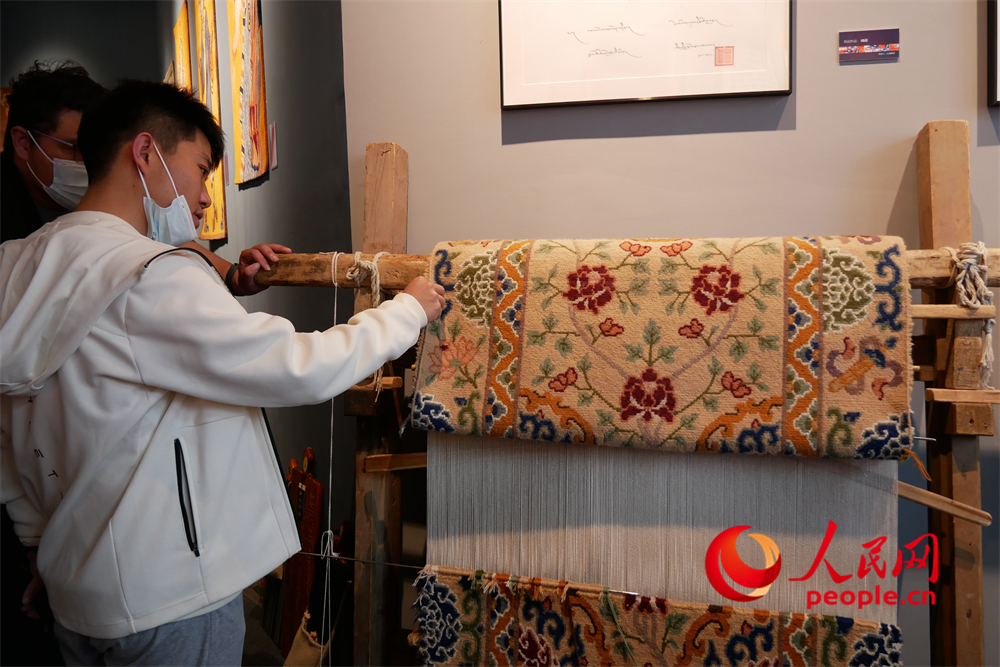 觀眾正在觀賞展出的藏毯。人民網 韋衍行攝