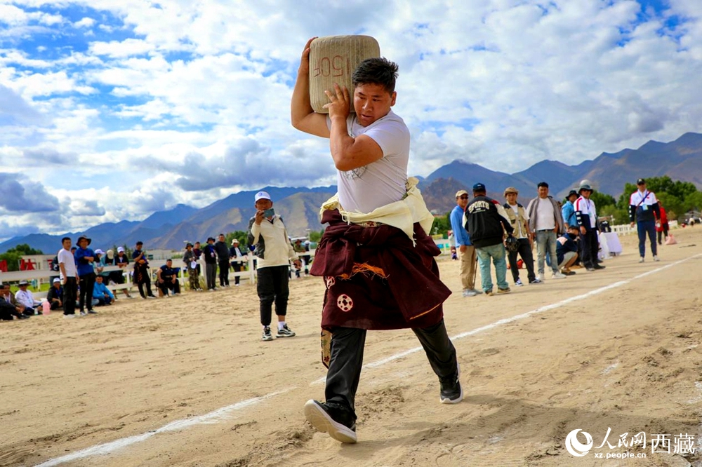來自拉薩市當雄縣的牧民選手將一塊150斤重的石頭扛在肩上飛奔。