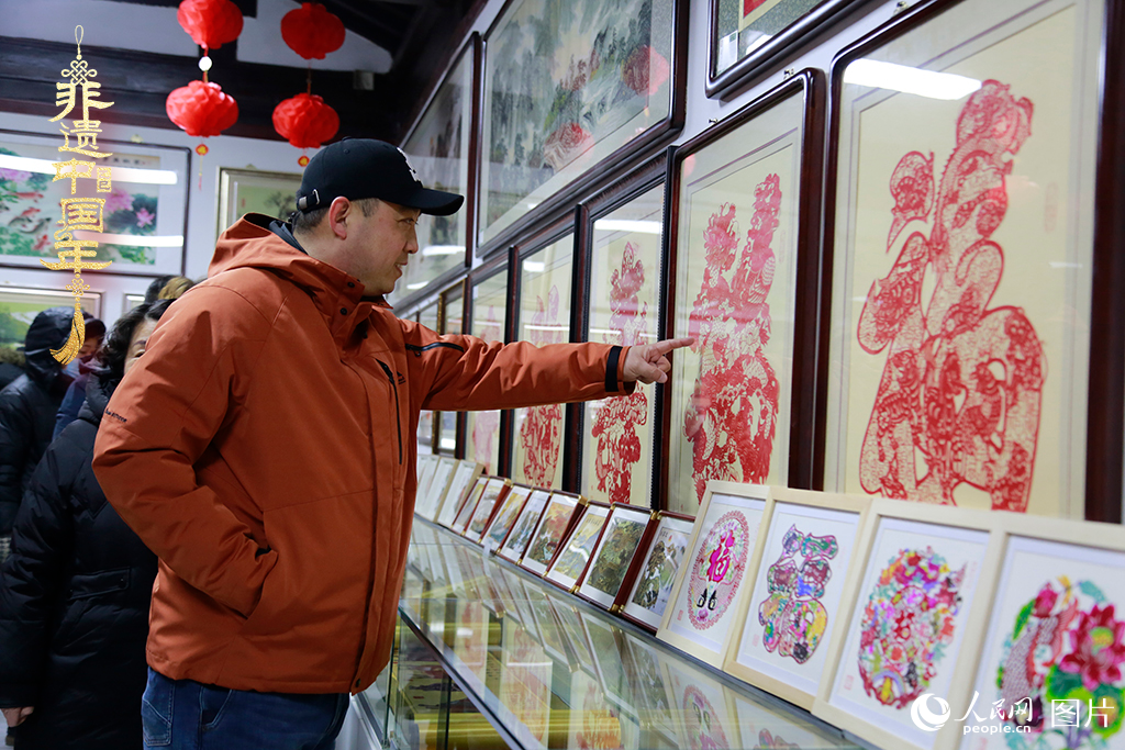 2025年1月23日，游客在天津楊柳青古鎮(zhèn)欣賞傳統(tǒng)剪紙作品，感受指尖上的古老藝術(shù)。人民網(wǎng)記者 崔新耀攝